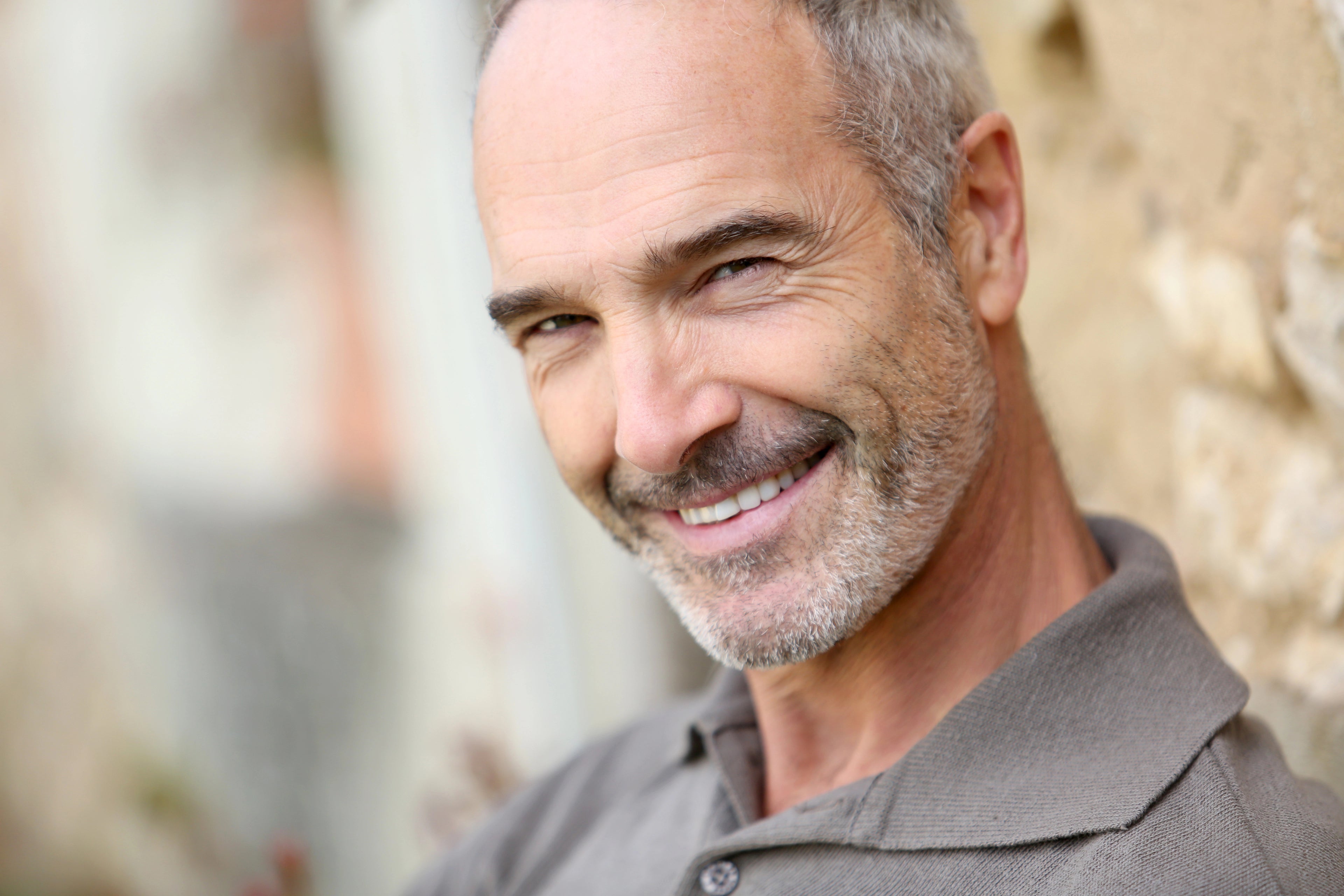 Man with gray hair and beard smiling outdoors