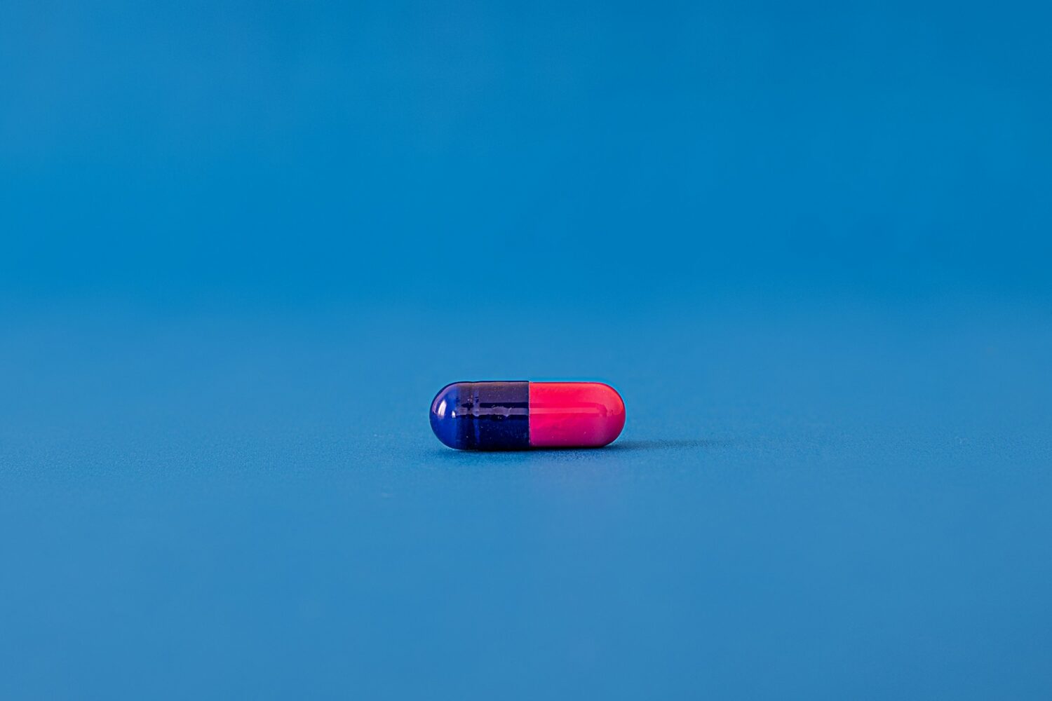 red and blue pill on blue surface, representing a narcotic in article answering is alcohol a narcotic