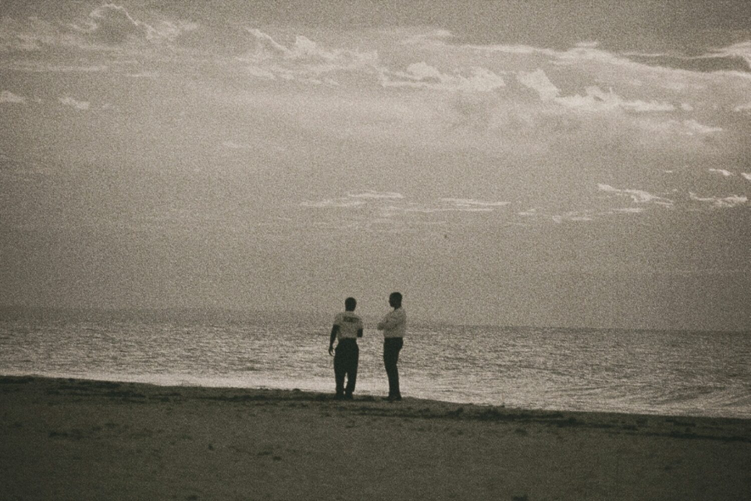 a couple of men standing on top of a sandy beach