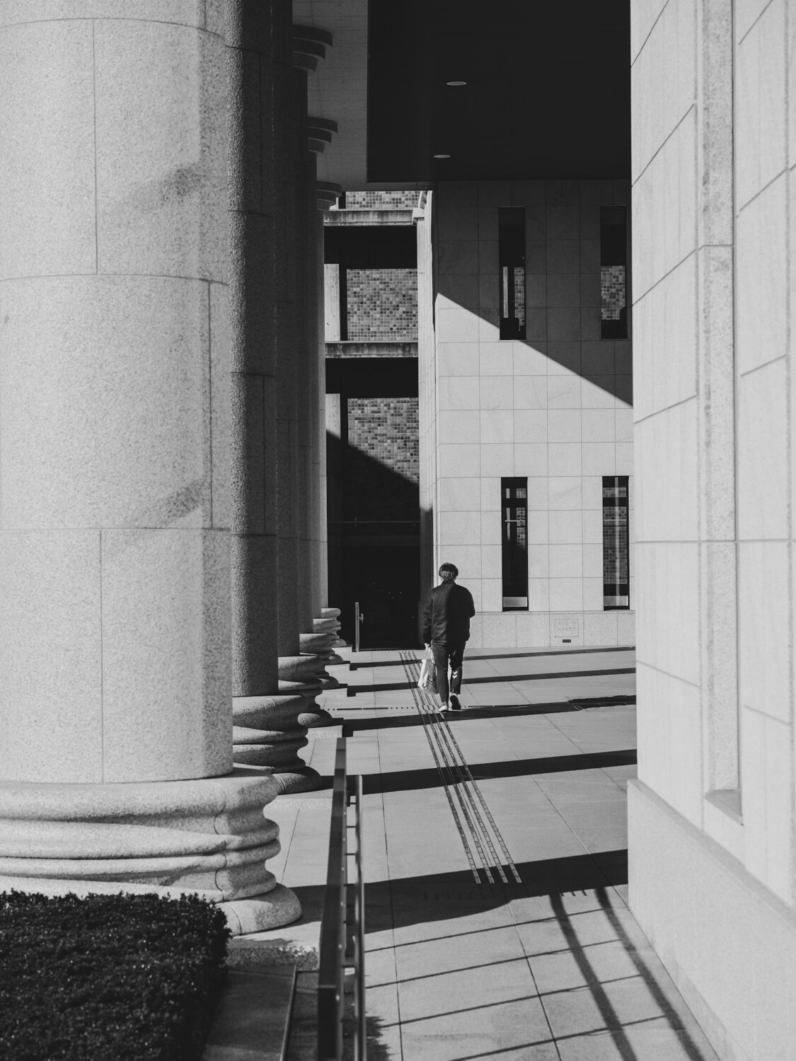 A black and white photo of a man walking down the steps of a building