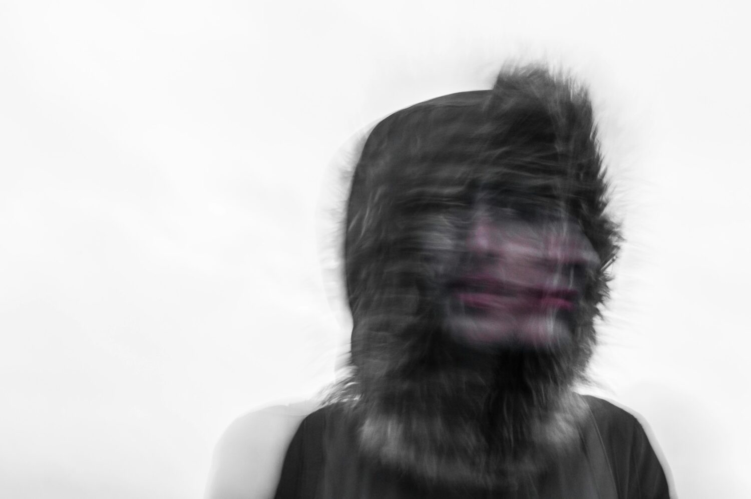 Blurred photo of a person's face and a furry hood, representing a hallucination in an article answering is alcohol a narcotic