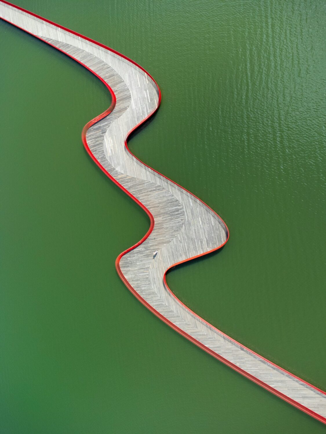 A winding bridge over green water.