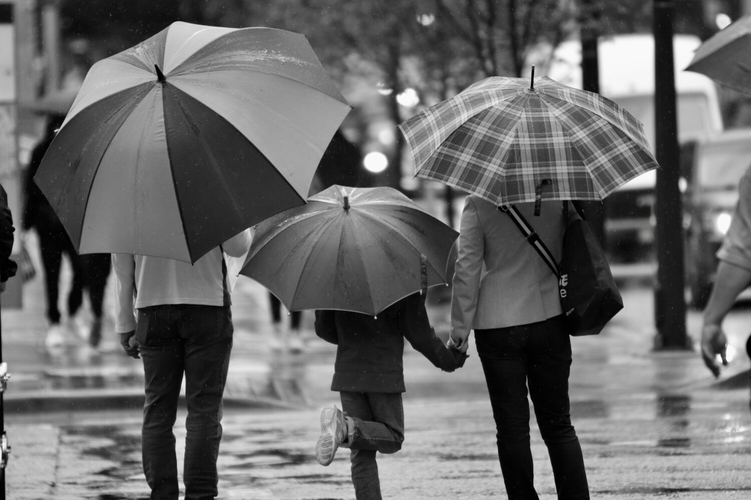 grayscale photography of three person's holding umbrella - image for can a parent lose custody for not co parenting
